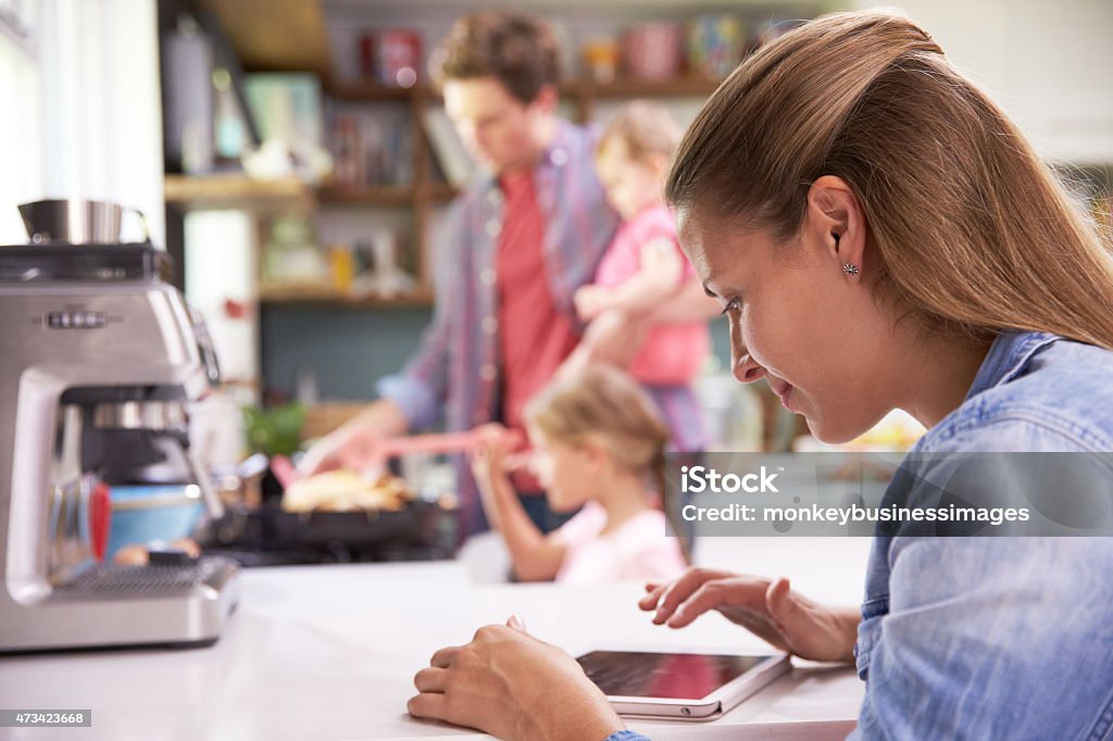 Pai Cooks refeição para a família enquanto a mãe usa Tablet Digital - Foto de stock de 20 Anos royalty-free