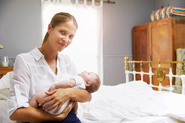 istock Mother Dressed For Work Holding Baby In Bedroom 473424486