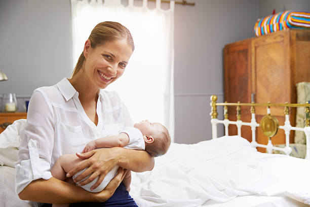 istock Mother Dressed For Work Holding Baby In Bedroom 473424492