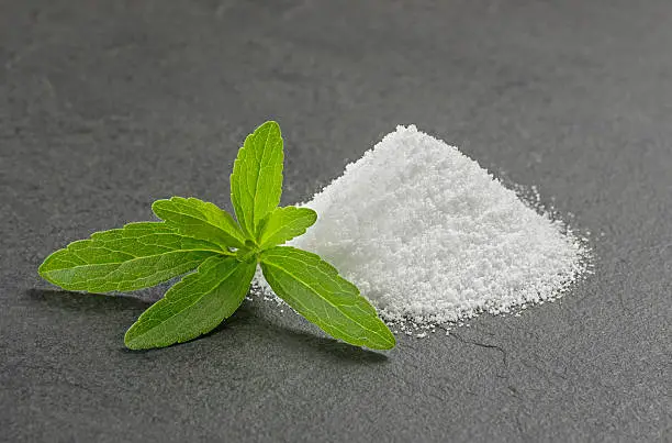 Stevia leaves with stevia powder on a slate plate