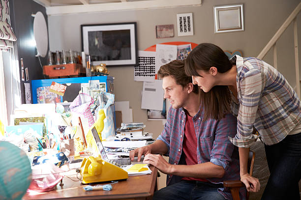 istock A man is sitting at a laptop while a woman looks over him 473429238