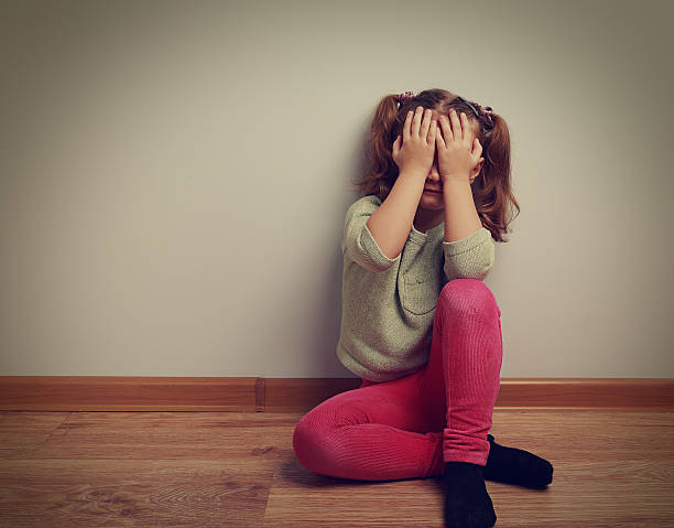 istock Frightened crying kid girl sitting on the floor 473434094