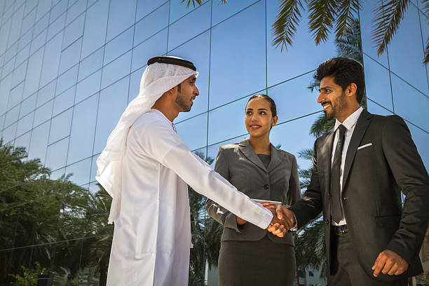 istock Businessmen shaking hands woman looking at them 473435098