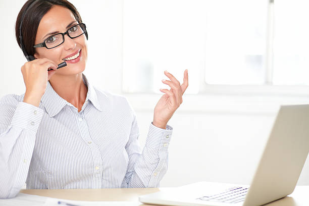 istock Latin girl receptionist conversing on her earphone 473438574