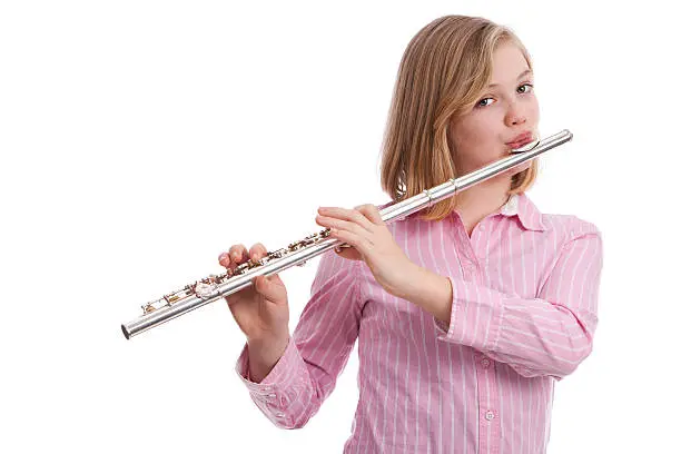 Attractive preteen playing her flute.  Isolated on white.