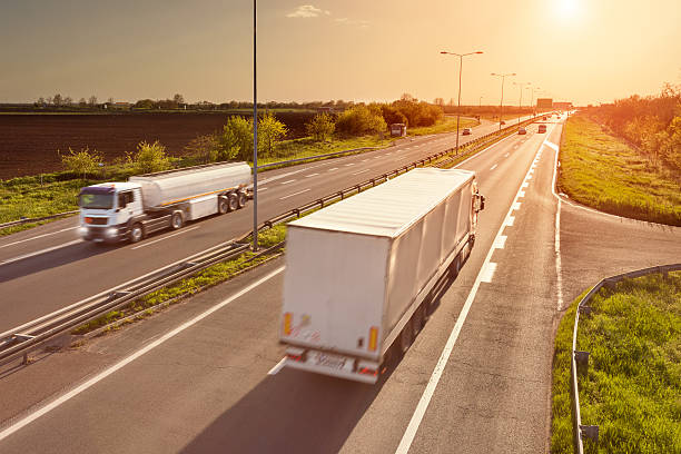 istock Two white trucks on the highway at sunset 473439050