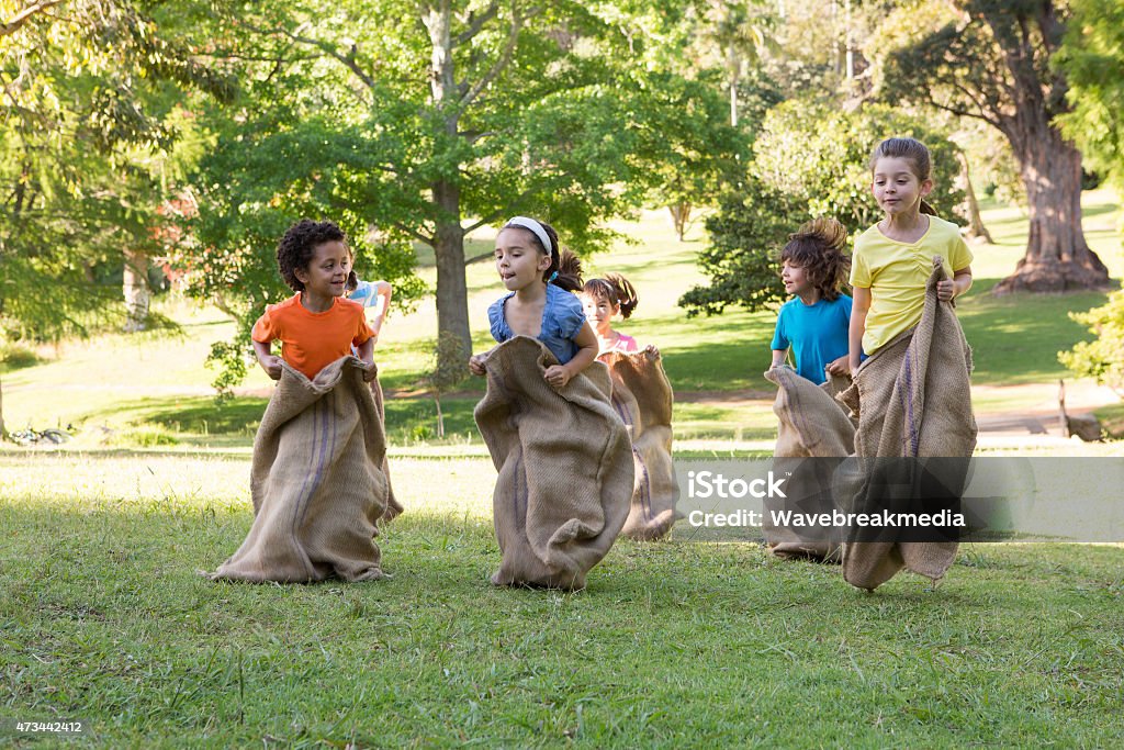 Children having a sack race in park Children having a sack race in park on a sunny day Child Stock Photo