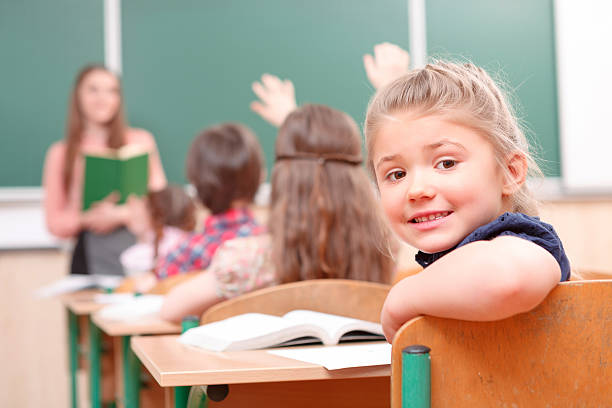 istock Pupil raising hand turned away from teacher 473442636