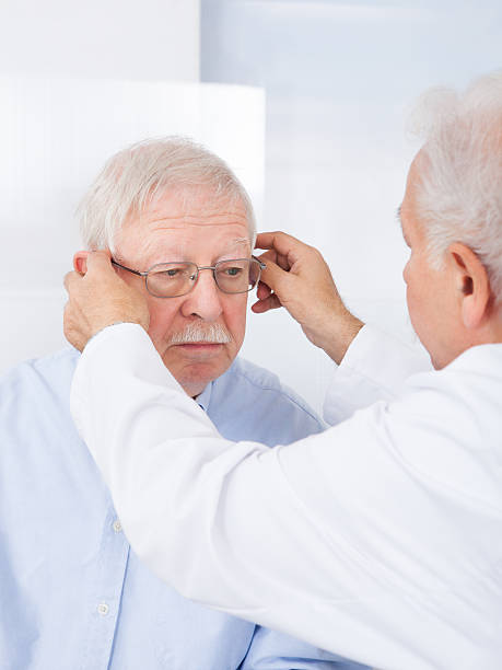 istock Optician Putting Glasses To Senior Man 473443416