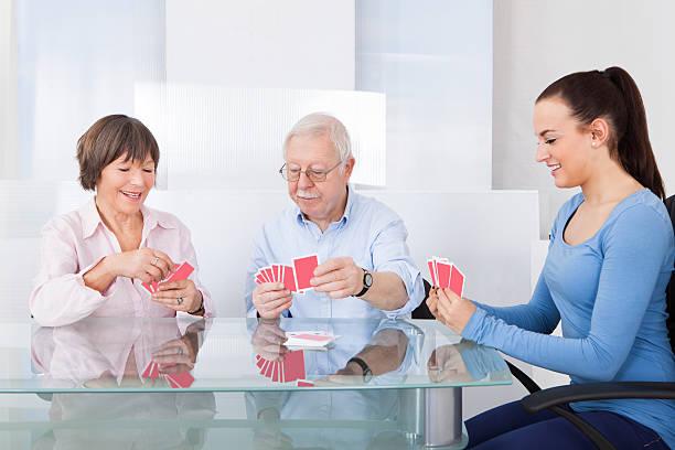 istock Caretaker playing cards with senior couple and smiling 473443502