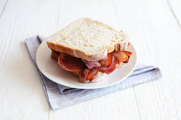 Simple bacon and bread sandwich over a blue tablecloth