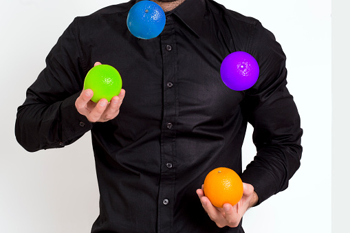 Man in black shirt juggling with multicolored oranges