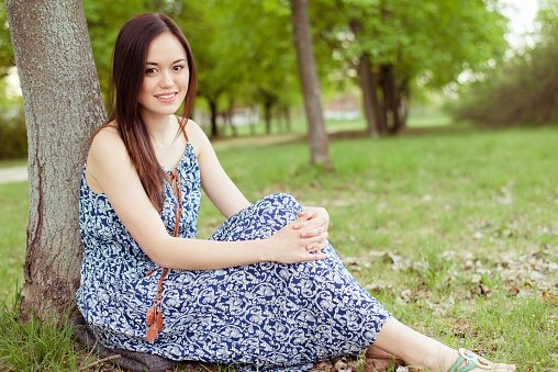 Summer girl portrait. Asian woman smiling happy on sunny summer day outside in park