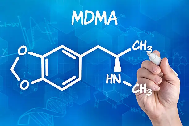Photo of hand with pen drawing the chemical formula of MDMA