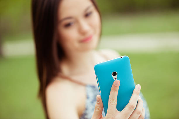 istock Smiling asian girl taking self portrait using smart phone 473455996