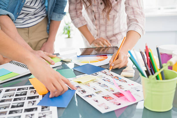 istock Coworkers briefing and editing photos together 473457580