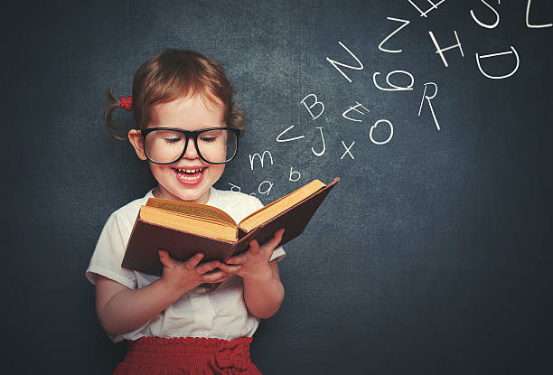 kleines mädchen mit brille lesen ein buch, mit abreise buchstaben - alphabet childhood learning education stock-fotos und bilder