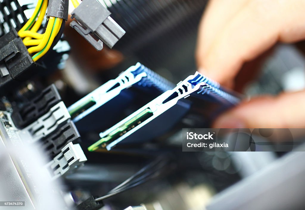 Installing RAM memory chip. Unrecognizable adult caucasian man installing RAM memory chip into  memory slot. There are eight available slots but only two visible. It's an 8 GB memory module. Random Access Memory Stock Photo