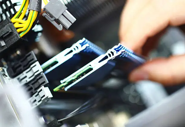 Unrecognizable adult caucasian man installing RAM memory chip into  memory slot. There are eight available slots but only two visible. It's an 8 GB memory module.