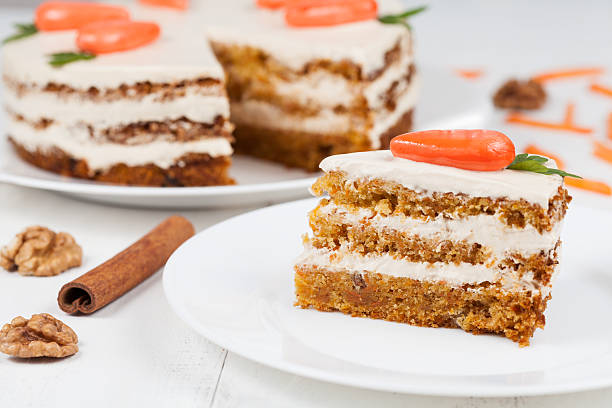 Delicious slice of carrot sponge cake with icing cream and Delicious slice of carrot sponge cake with icing cream and little orange carrots on white background walnut cookies stock pictures, royalty-free photos & images