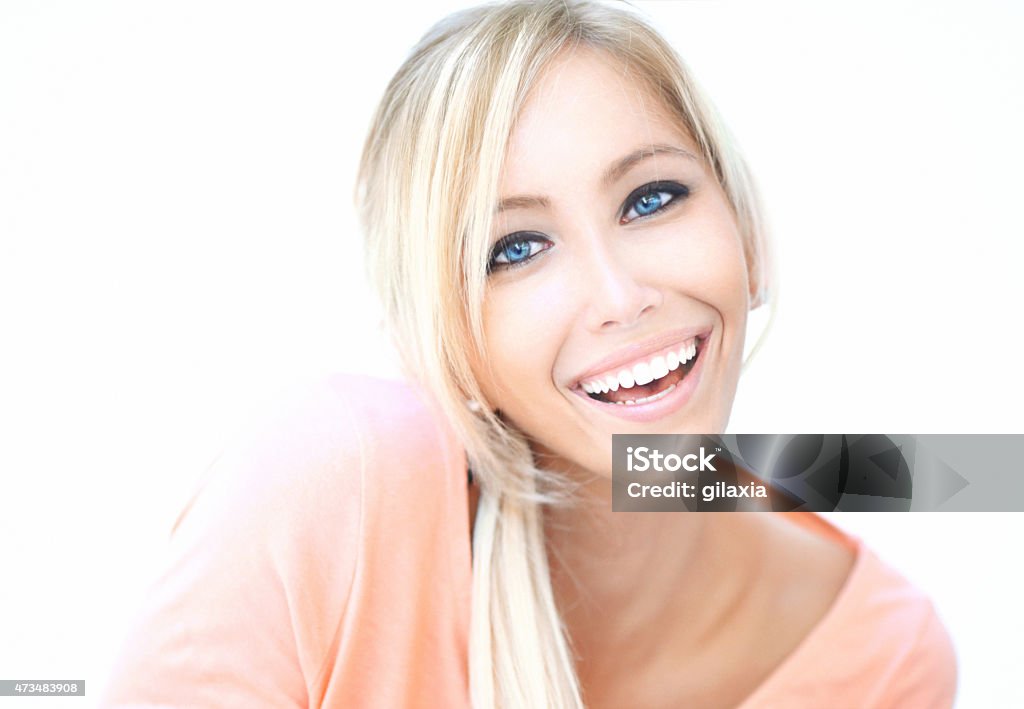 Portrait of smiling blond woman. Closeup portrait of smiling late 20's caucasian woman.She has sparkling blue eyes and nice set of teeth.Her har is straight, falling on her shoulder.Wearing coral colored shirt. Looking at camera. 20-29 Years Stock Photo