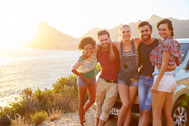 istock Friends Standing By Car On Coastal Road At Sunset 473486570