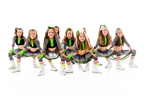 Team of happy little dancers standing in dance move and looking at the camera. Isolated on white.