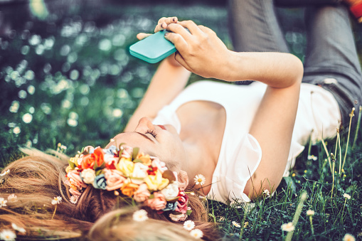 Beautiful young blonde girl is wearing a hair wreath and taking selfles 