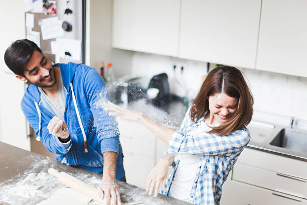 pareja joven cocinar juntos en casa. - haciendo burla fotografías e imágenes de stock