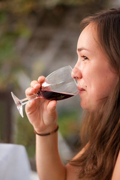 istock Young woman drinking red wine from a wineglass 473502841