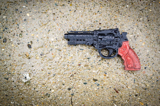 Rain soaks into a stone and plastic toy gun in black and brown