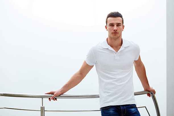 istock Man in a polo shirt stands leaning on railing 473512784