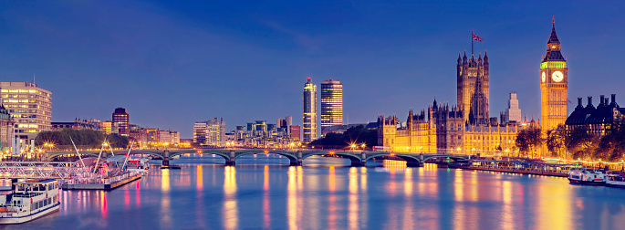 London Cityscape with landmarks including Westmisnter Bridge, The Houses of Parliament and Portcullis House at dusk.