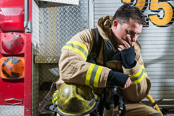 istock Fireman sitting on fire truck tired and sad 473517424