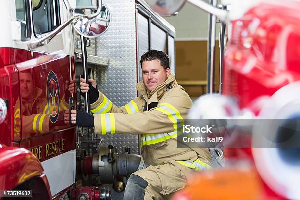 Fireman At Station Ready To Climb On Fire Truck Stock Photo - Download Image Now - Men, Moving Up, Truck