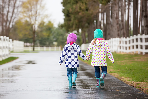 Two Young Girls Holding Hands Walking in Rain