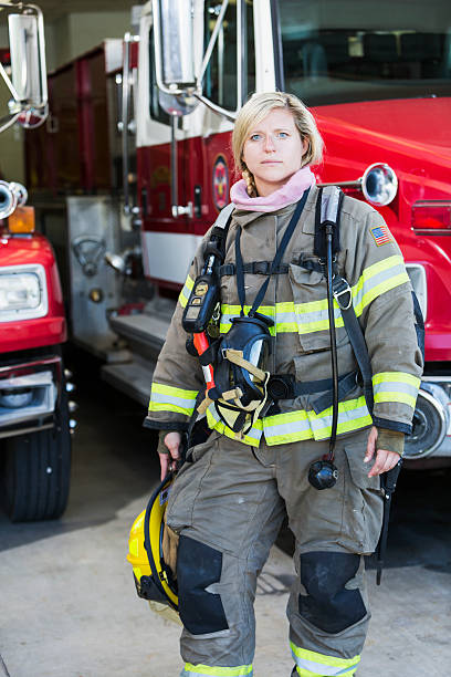istock Female firefighter standing in front of fire truck 473525618
