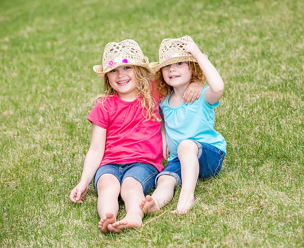 istock Two Sisters Sitting In Grass With Arms Around Each Other 473529642