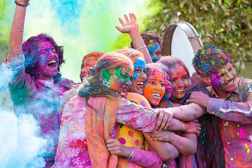 Group of young Indian friends covered in colored dye celebrating Holi festival in Jaipur, India.