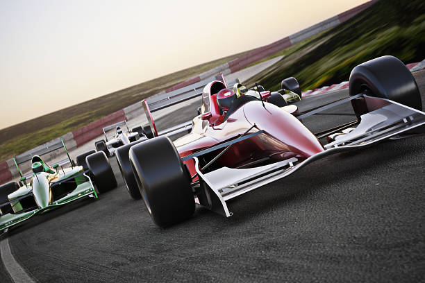 rojo coches de carrera en una pista a la vanguardia - racecar fotografías e imágenes de stock