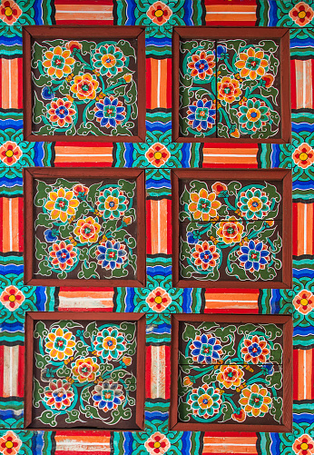 Old painted wooden ceiling in bright colors with lotus flowers at the Changdeokgung Palace in Seoul, South Korea..
