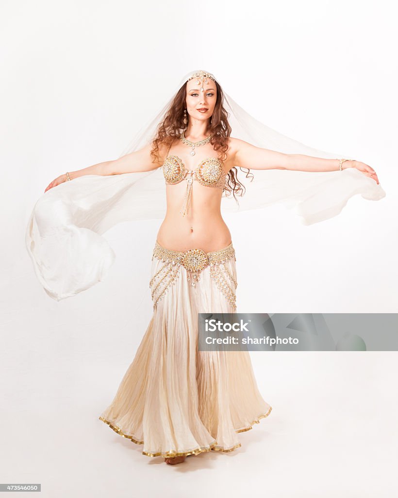 Beautiful belly dancer  turning with veil A beautiful young belly dancer dressed in white turns with her veil out. Motion blur on the veil, sharp on face and body. 2015 Stock Photo