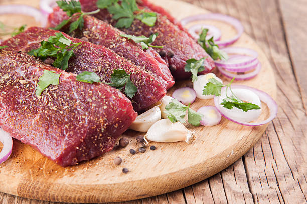 istock Raw beef steaks with parsley, garlic and onions 473550586