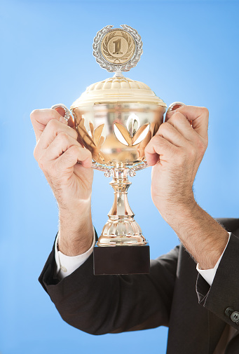 Portrait of senior businessmen holding a trophy on sky