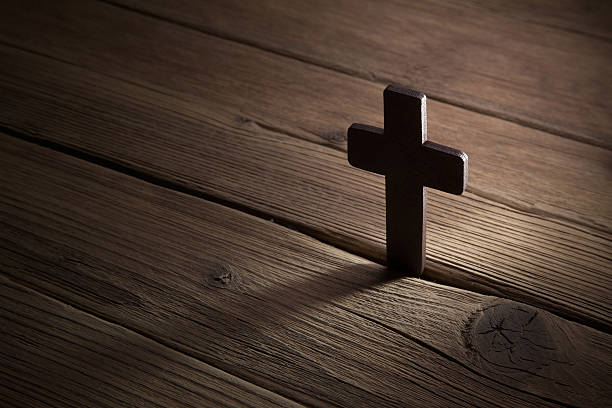 istock wooden cross on wood background 473551636