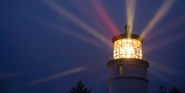 Lighthouse Beams Illumination Into Rain Storm Maritime Nautical A perfect storm is just the right weather to make a lighthouse earn its keep for weary travelers distant photos stock pictures, royalty-free photos & images