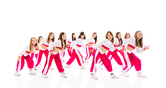 Dance group of little girls standing in a dance move and looking at camera. Isolated on white.