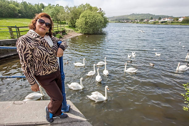 Mature smiling hispanic woman portrait at lakeside with swans and ducks