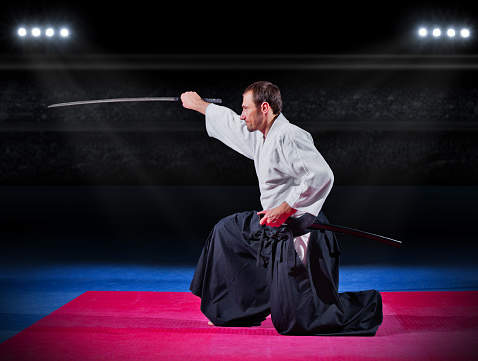 Aikido fighter with sword at sports hall
