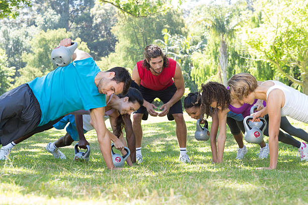 istock Fitness group planking in park with coach 473572322